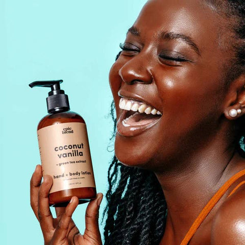 Woman holding a bottle of coconut vanilla lotion against a light blue background