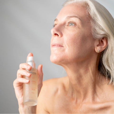 Woman holding a skincare bottle against a gray background